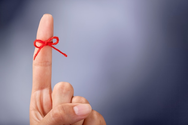 Photo red thread bow on a human finger