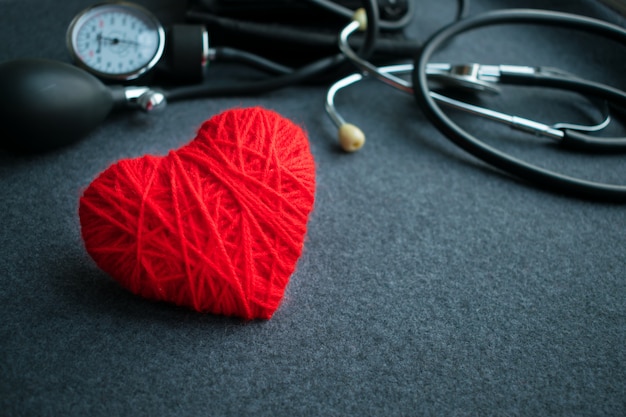 Red thread heart with tonometer on grey table