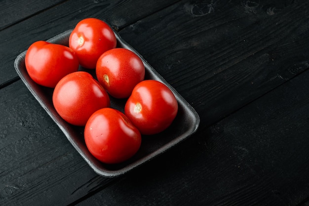 Red tomatoes, on black wooden table