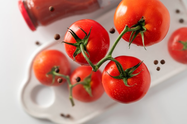 Pomodori rossi su un ramo una bottiglia di passata di pomodoro