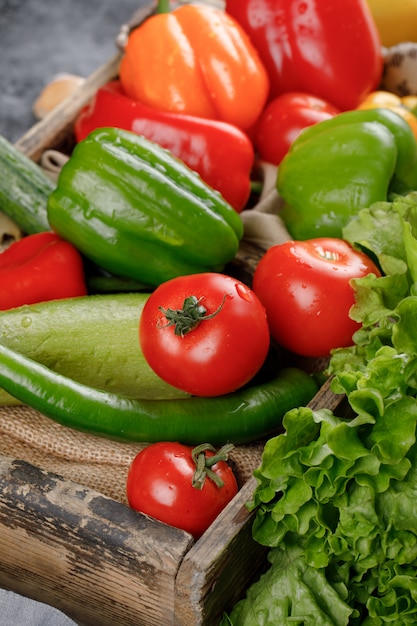 Red tomatoes, chilies and cucumbers on rustic tray.