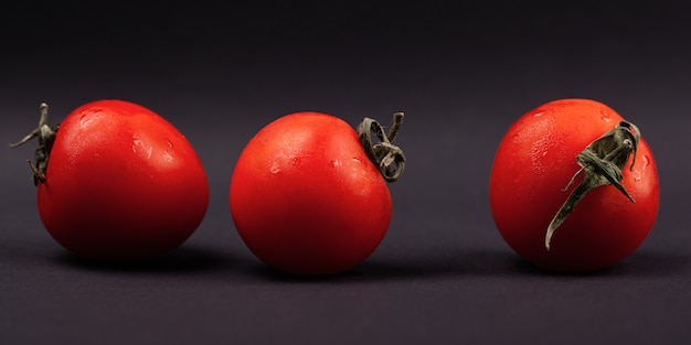 Photo red tomatoes on a dark background close-up, panorama.