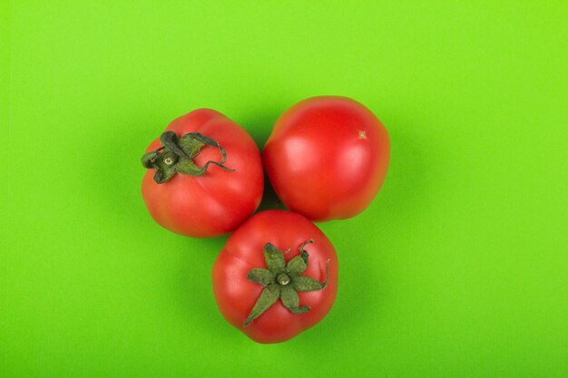 Red tomatoes on green background