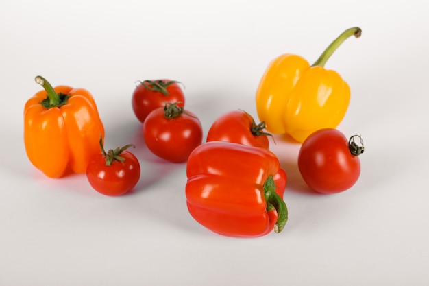 Red tomatoes and peppers on white with shadows. top view