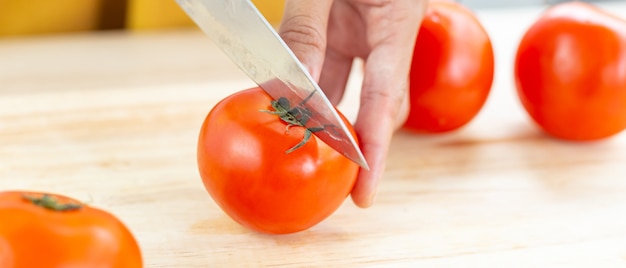 Red tomatoes and slices on wooden cutting board