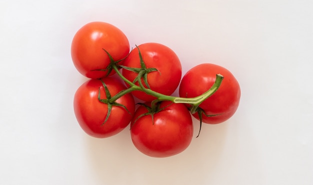 Red tomatoes on a twig on a white background