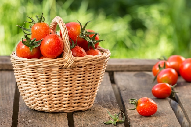 Red tomatoes in wicker basket on  wooden table