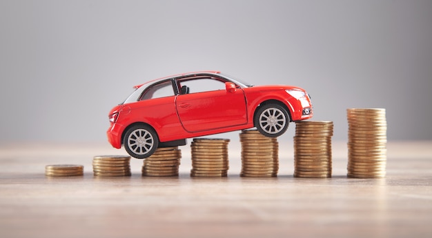 Red toy car and coins on the desk.