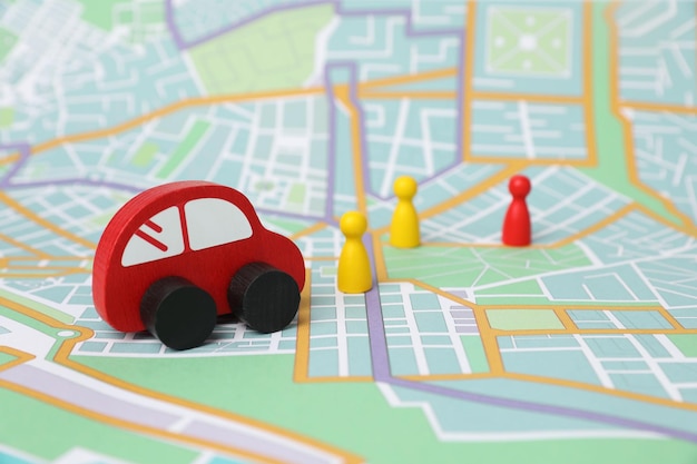red toy car and colorful human figures on city map road trip