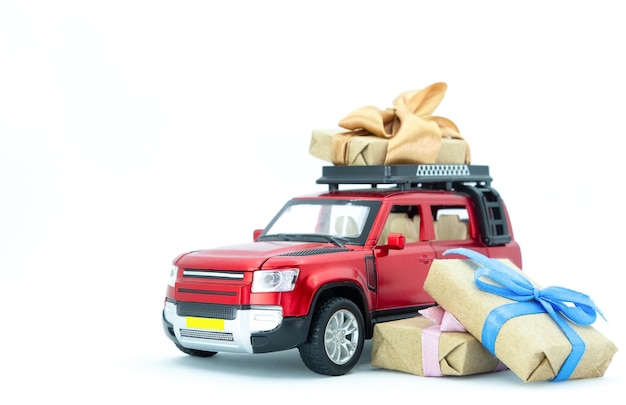 Red toy car delivering gift boxex present on white background copy space
