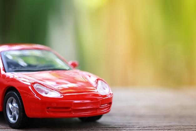 Red toy car on wooden floor.