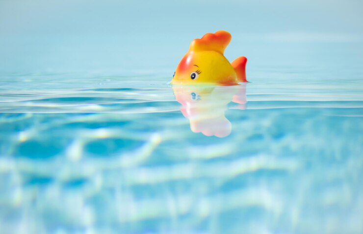 Photo 赤いおもちゃの魚がプールで風呂を浴びている 浅いフィールドとコピースペースの深さ