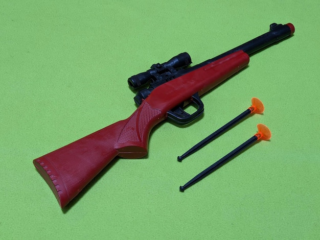 Красный игрушечный пистолет на зеленом фоне