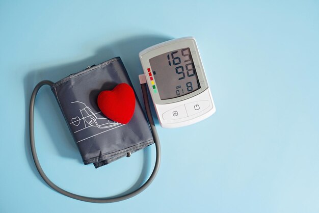 Red toy heart and tonometer on a blue background Healthcare concept Cardiology Caring for the Heart