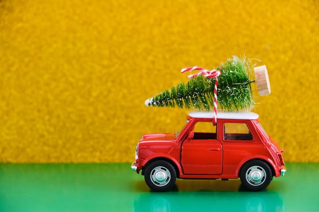 Red toy retro car delivering a gift on green-yellow
