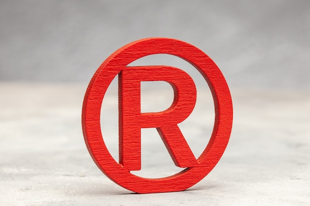 Red trademark sign on gray surface.