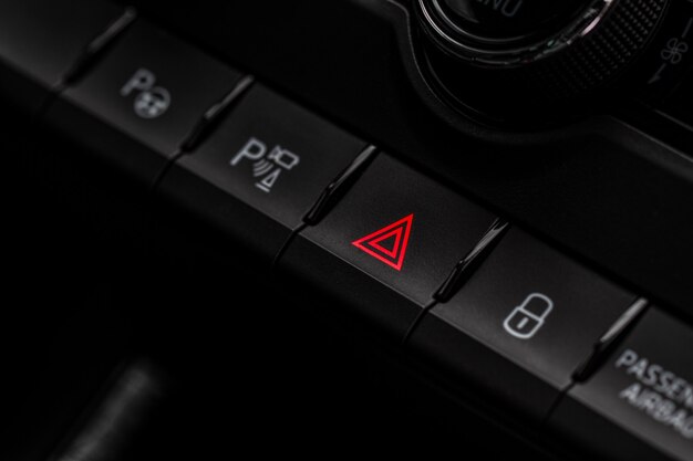 Red triangle hazard light button on car dashboard. Car media buttons dashboard. Detail of a modern car controllers.