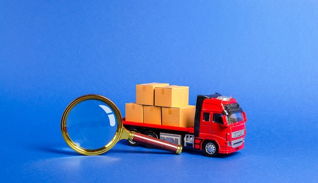 Red truck loaded with boxes and a magnifying glass Search for a carrier for transportation