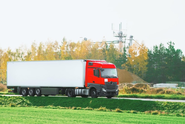 A red truck transports goods across a picturesque landscape illuminated by the golden hue of the setting sun Truck transportation