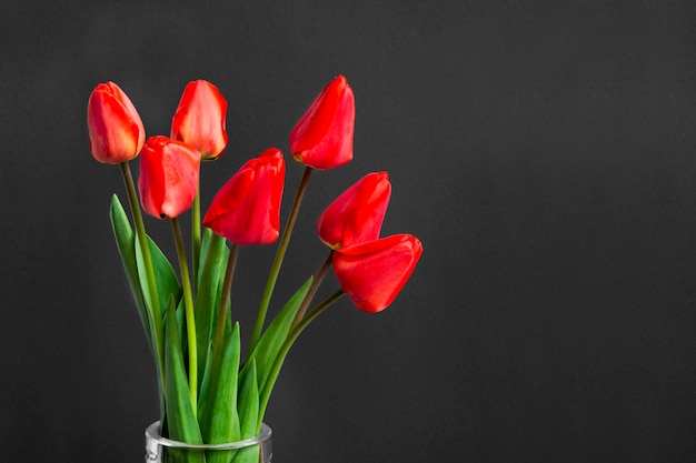 Red tulips on a black background Place for text Bouquet