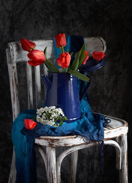 Red tulips bouquet in blue vase on vintage cher