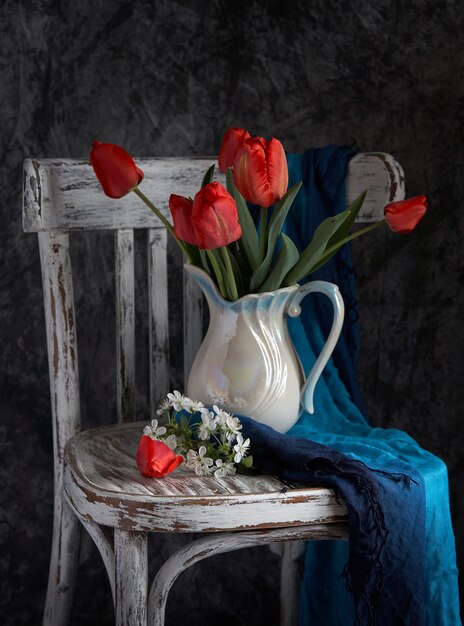 Red tulips bouquet in white vase on vintage cher