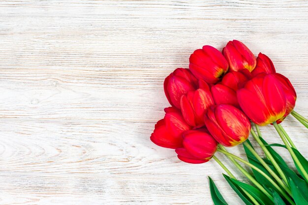 Red tulips flowers bouquet on old white wooden background Top view with copy space