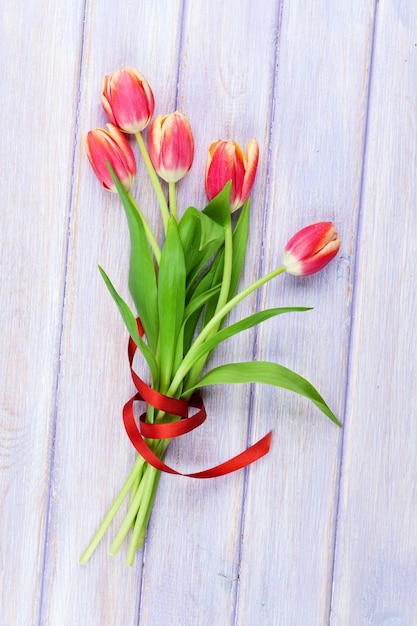 Red tulips over purple wooden table