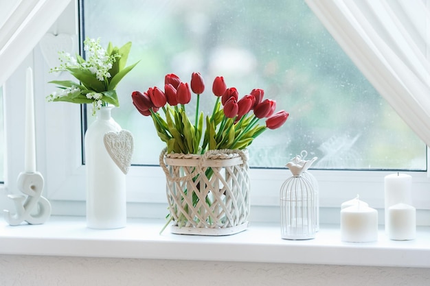 Red tulips and snowdrops in basket on box