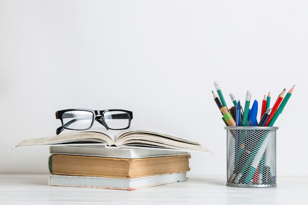 Red tulips in a vase, books and school supplies on white.