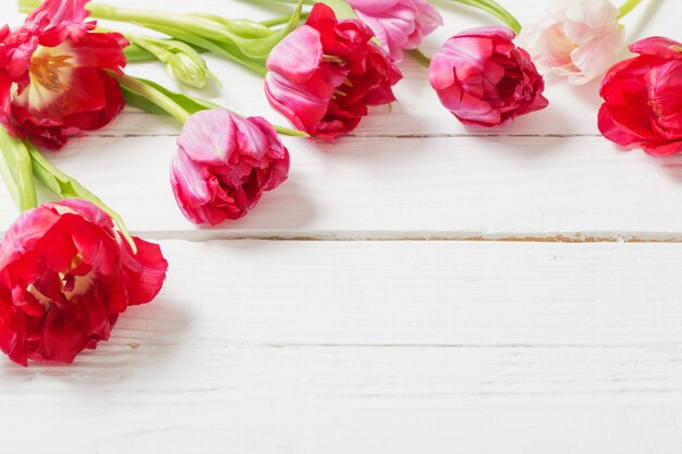 Red tulips on white wooden table