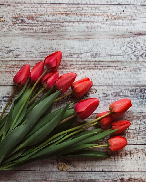 Red tulips with leaves lie on a wooden background