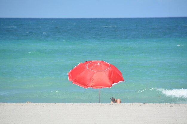 Foto ombrello rosso sulla spiaggia contro un cielo blu limpido