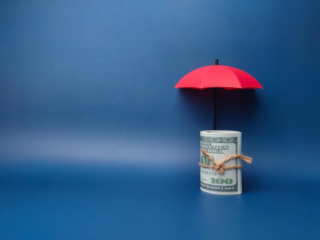 Photo a red umbrella protecting banknotes on a blue background with copy space planning saving families preventing risks and crises health care and insurance concepts