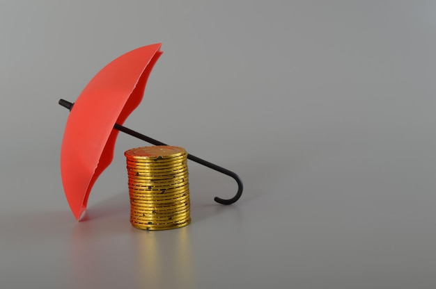Красный зонт и стопка монет Сохранение денег в безопасности Защита сбережений Концепция страхования инвестиций и капитала