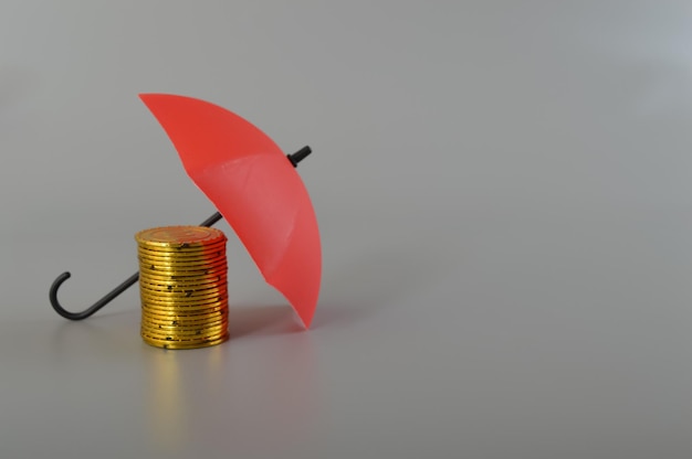 Red umbrella and the stack of coins keeping money safe savings\
protection investment and capital insurance concept