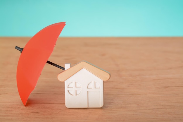 빨간 우산과 복사 공간이 있는 장난감 집 가정 보호 및 안전 보장 개념