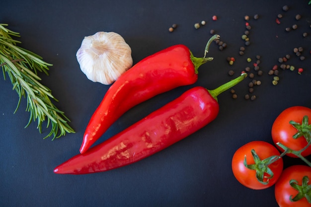 Red vegetables on a black background Peppers and tomatoes garlic