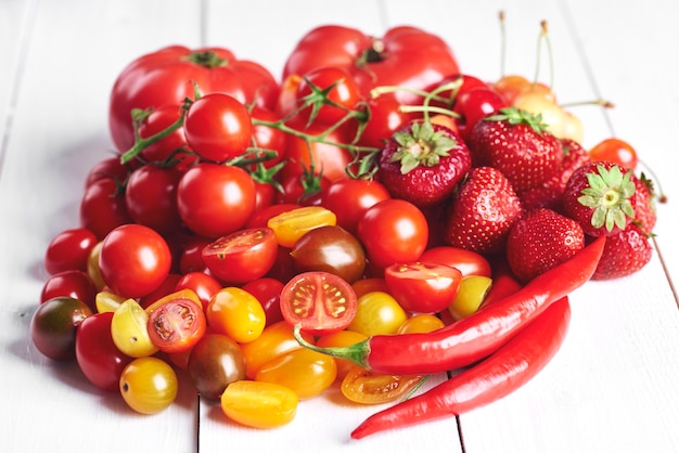 Red vegetables and fruit on white wood