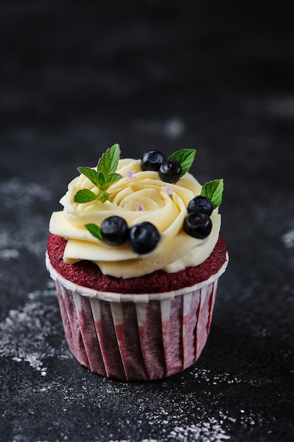 Red velvet cupcakes met cream cheese cream. Dessert gegarneerd met verse bosbessen en munt.