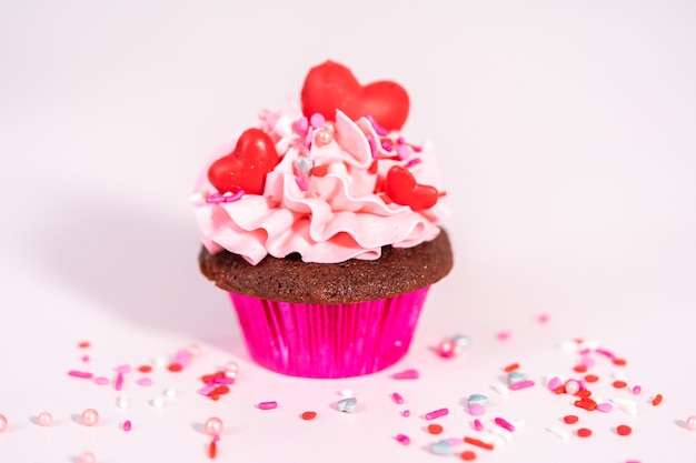 Red velvet cupcakes met roze Italiaanse botercrème frosting en gedecoreerd met hart en kusvormige rode chocolaatjes.