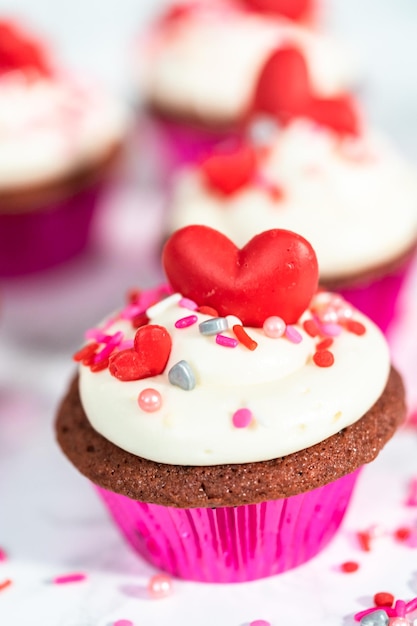 Red velvet cupcakes with cream cheese frosting and decorates with heart and kiss shaped red chocolates