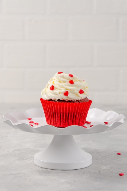 크림 치즈 아이싱을 곁들인 레드 벨벳 컵케이크는 발렌타인 데이를 위해 흰색 스탠드에 장식되어 있습니다.