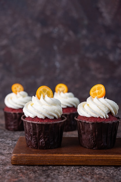 Cupcakes di velluto rosso con crema bianca sulla parte superiore decorata con fetta di kumquat.