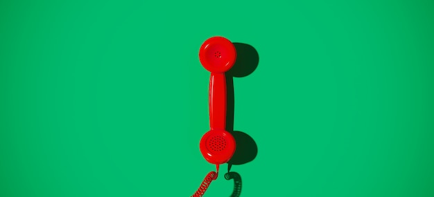 Красный старинный телефон на зеленом фоне