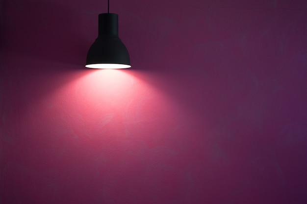 Фото Красная стена освещенная винтажной черной стильной лампой конуса.