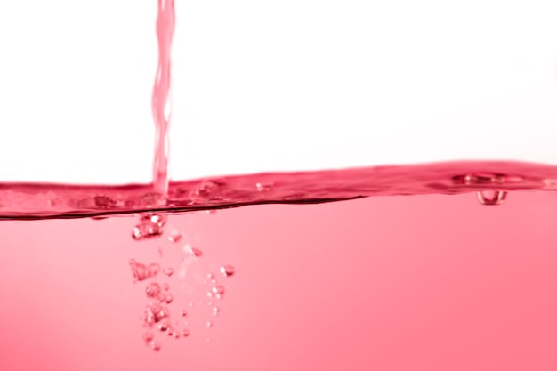 Фото Красная поверхность воды с брызгами и пузырьками на белом фоне