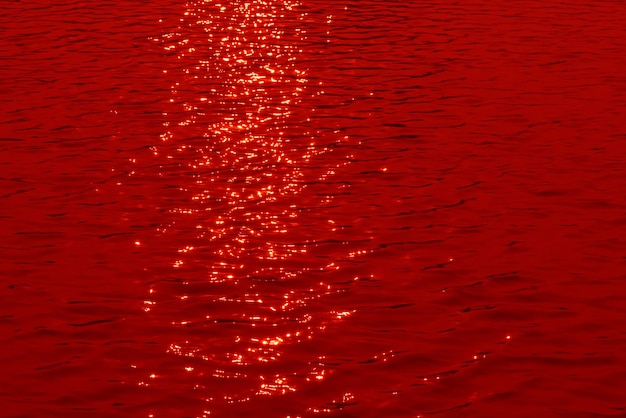 Red water with the sun reflecting on it transparent red colored clear calm water surface texture