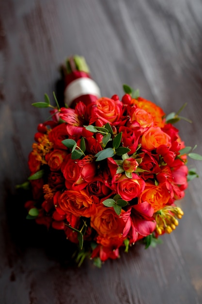 Red wedding bouquet on woodden background close up