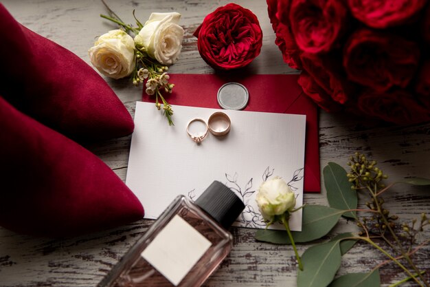 Red wedding. Wedding rings on white and red invitation near perfume bottle